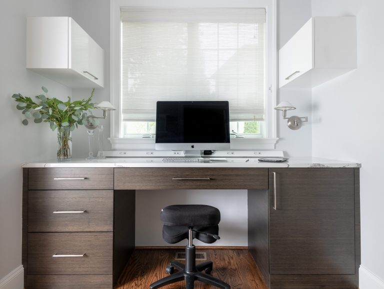 home office with desk under window, two side white cabinets facing window dressed in a white pull shade