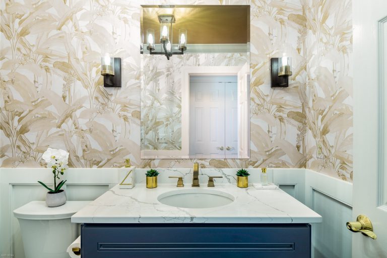 Case design bathroom white counter top and a shimmering golden wall with widespread 2- handle bathroom faucet in brushed gold
