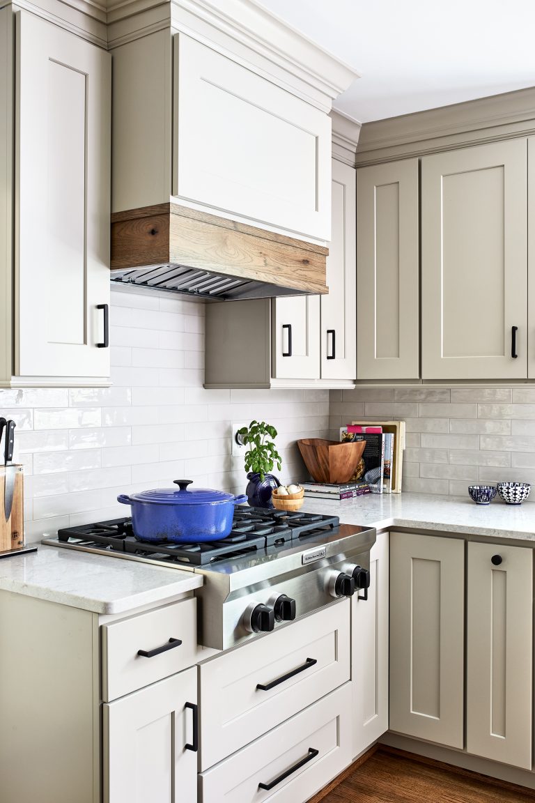 white cabinets with black pull handles, stove top 4 burners and wood hood range