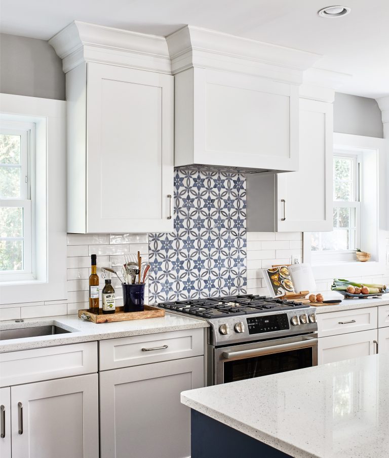 transitional kitchen in VA with 6 burner gas stove, blue/white backsplash and white cabinets with pull handles