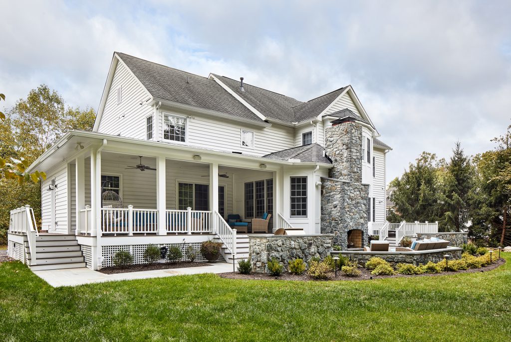 single home with field stone fireplace on outside, patio furniture facing the fireplace