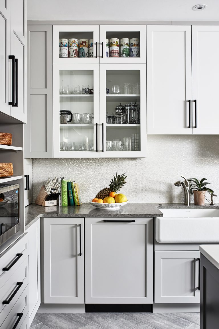 transitional kitchen with white glass cabinets with black pull handles