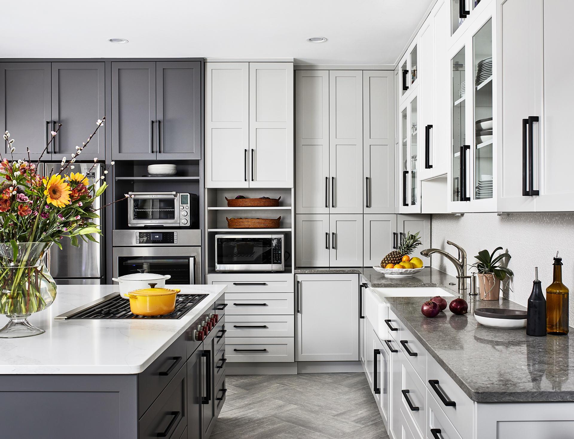 kitchen island with stove top and grey base, grey and white cabinets with black pull handles two open shelves