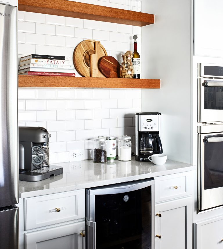 wood floating shelves suspended over white wash cabinets fitted with a glass front beverage fridge